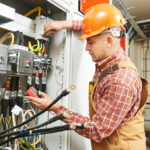 young adult electrician builder engineer worker in front of fuse switch board