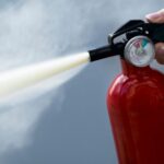 Woman using fire extinguisher, close-up